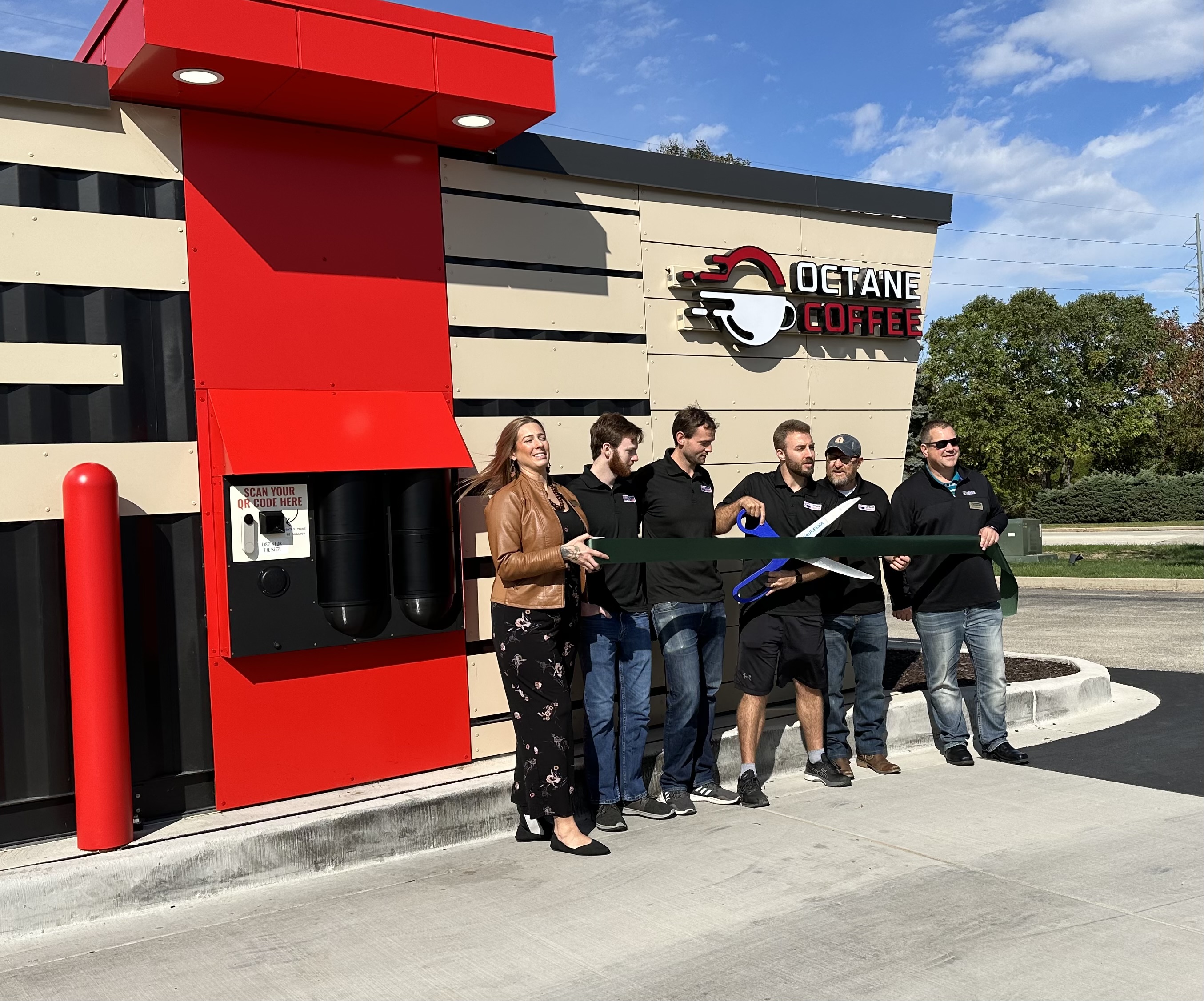 Six people stand in front of Octane Coffee kiosk.
