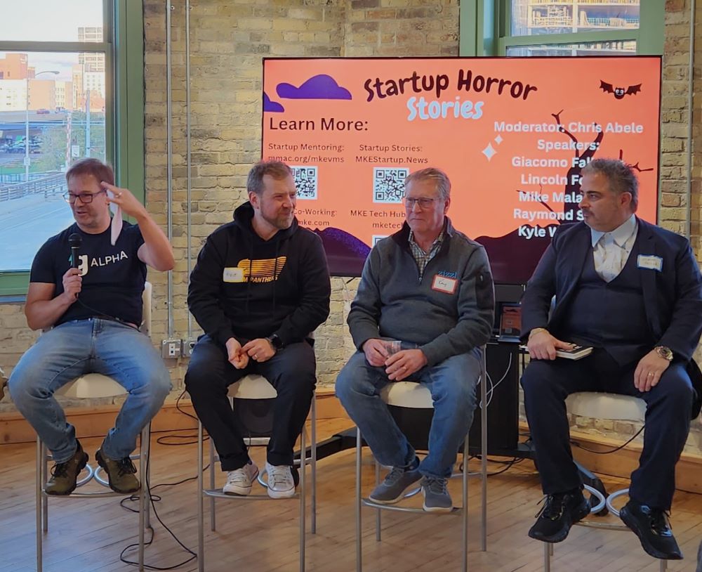 Four men sitting in high top chairs.