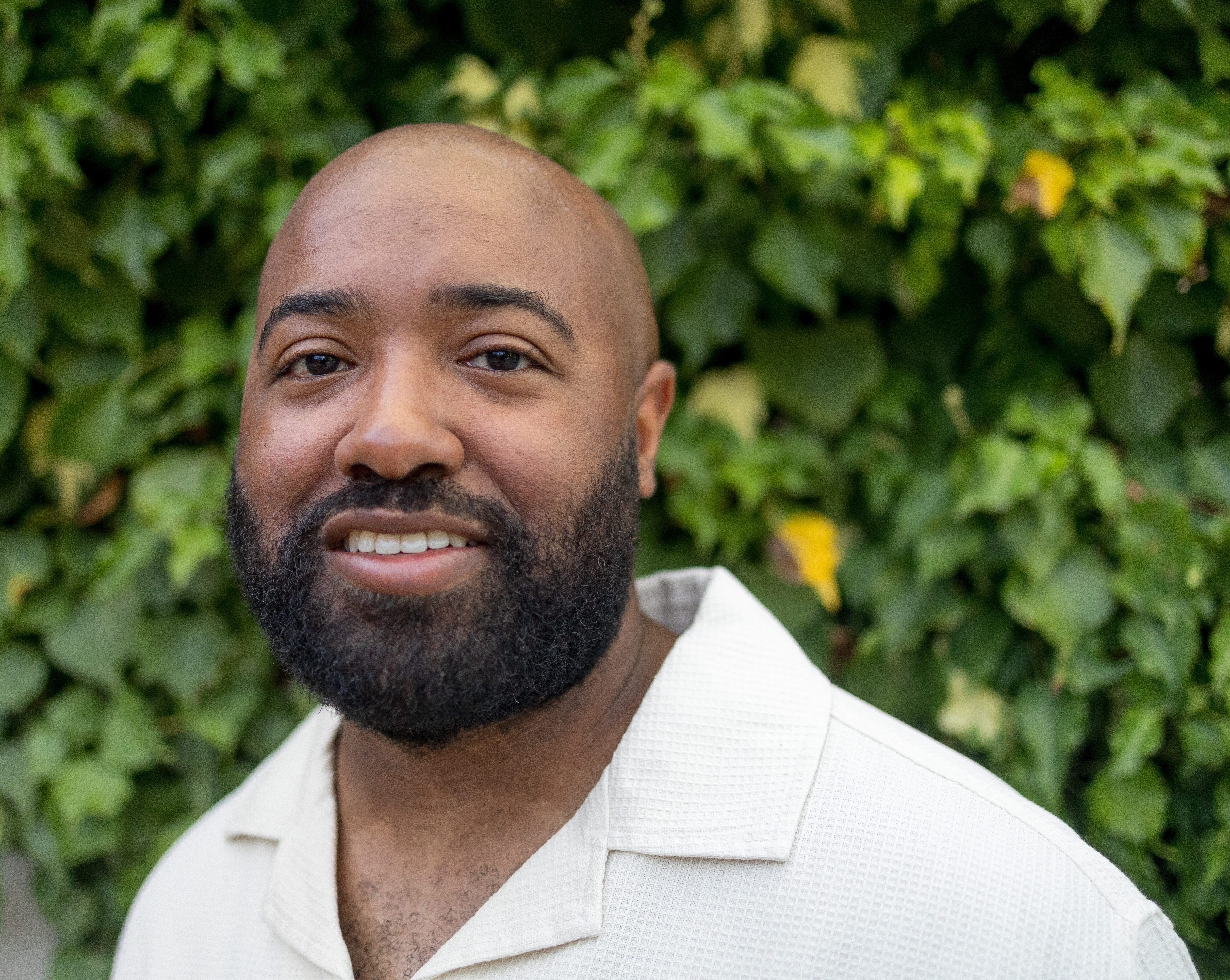 Man standing in front of bushes.