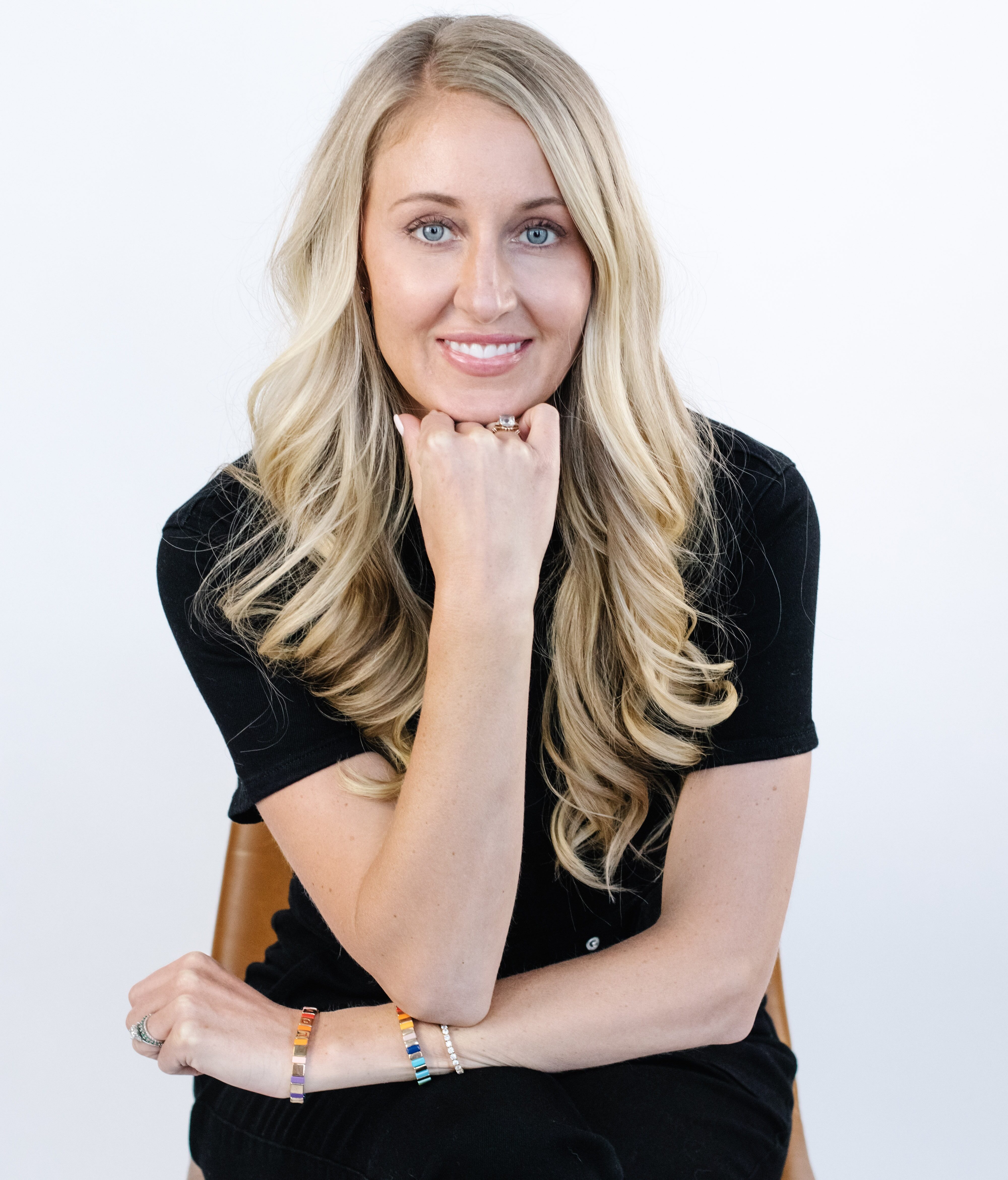 Blonde woman in a black shirt sitting in a chair.