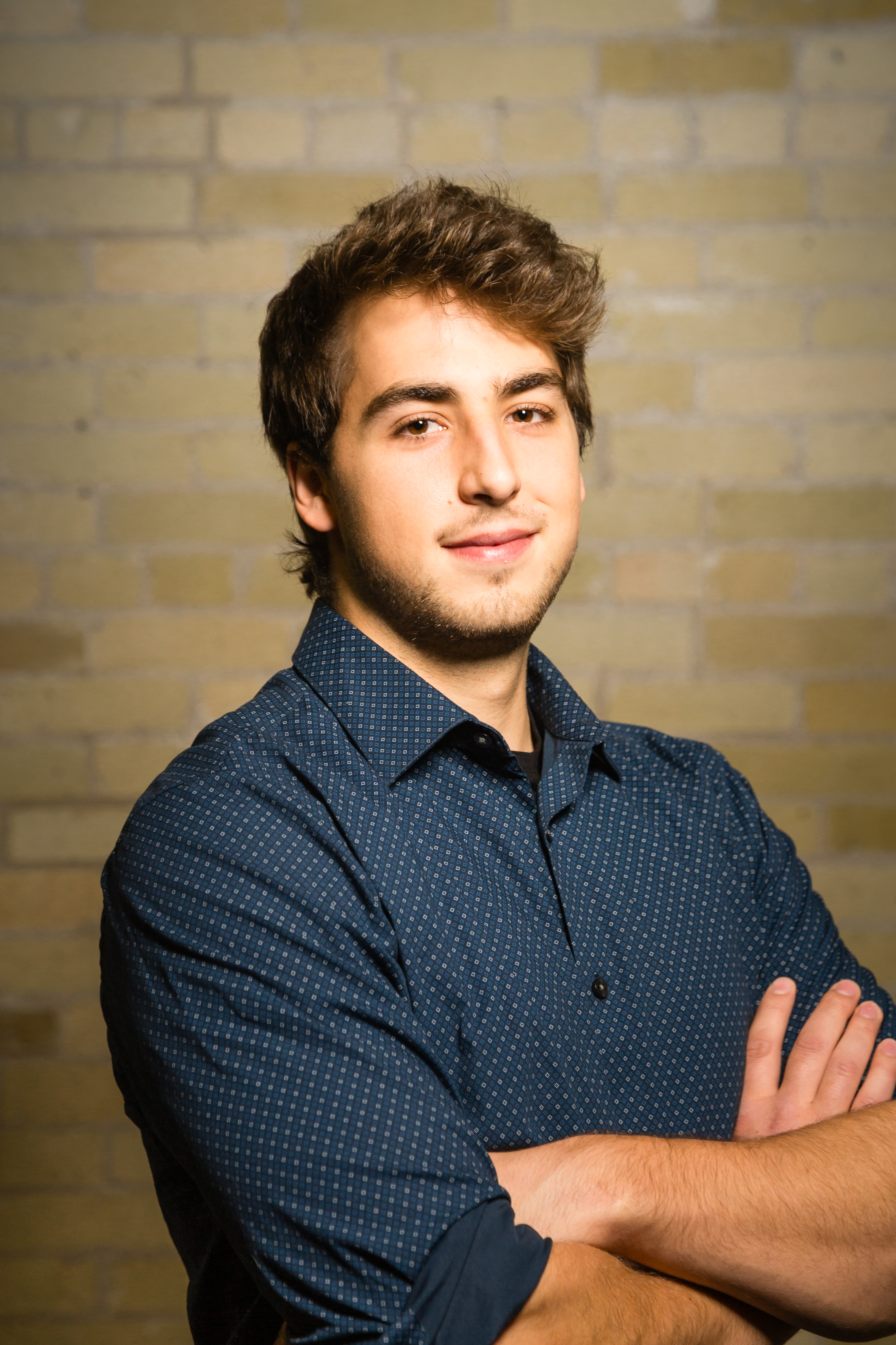 Man wearing blue shirt in front of brick wall